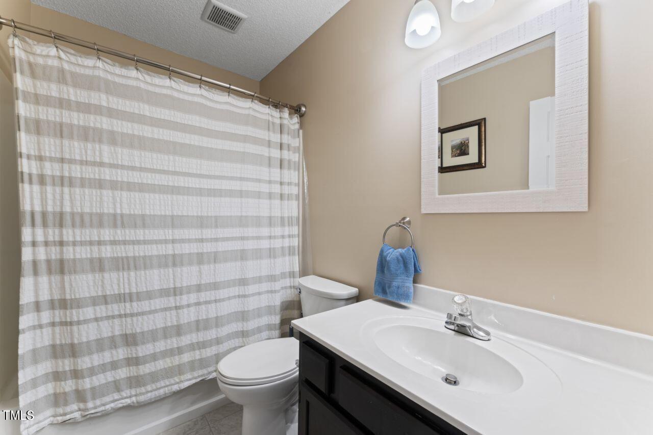 12129 Mabledon Court Raleigh, NC 27613 - Photo 25 of 31 a bathroom with a sink a toilet and mirror