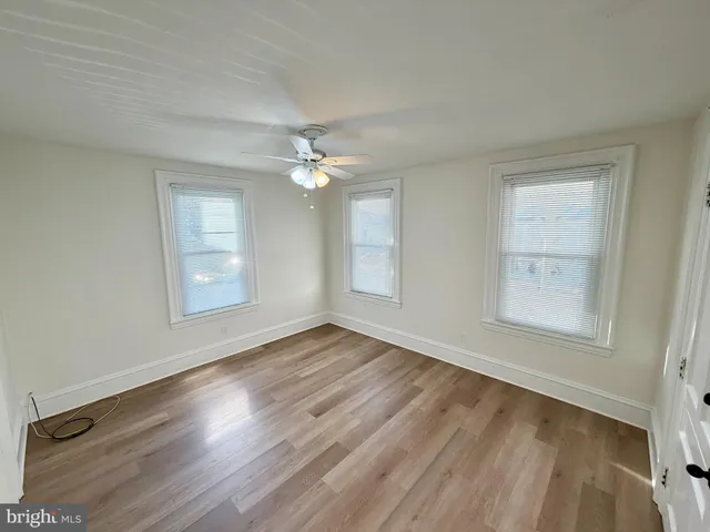 a view of an empty room with wooden floor and window
