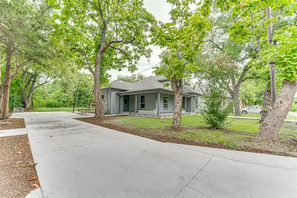a front view of a house with a garden and trees