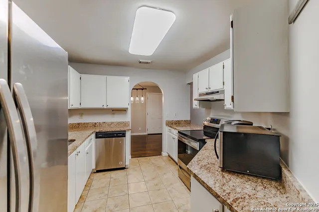 a kitchen with stainless steel appliances granite countertop a refrigerator stove top oven and sink