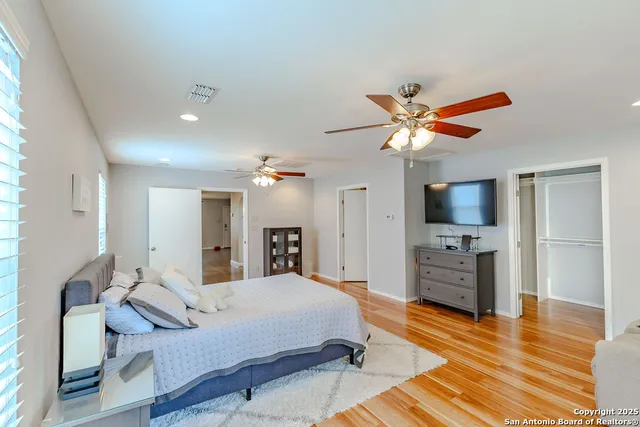 a spacious bedroom with a bed and a flat screen tv