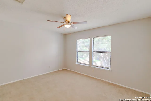 an empty room with a window and a fan