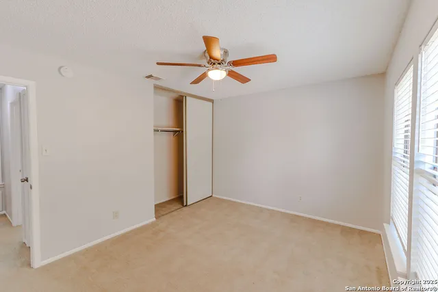 an empty room with a window and a fan