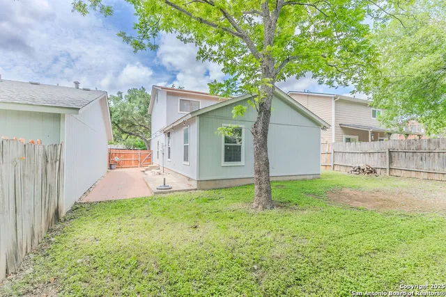 a view of a house with a yard and a large tree