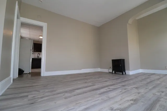a view of an empty room with wooden floor and closet