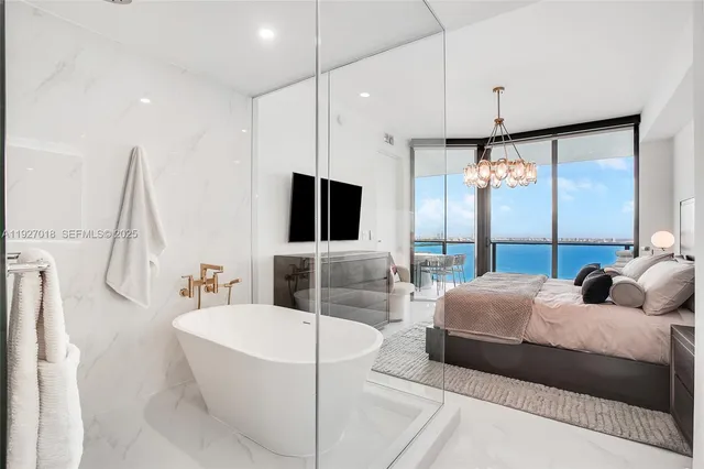 a bedroom with a bed a flat screen tv and a large window