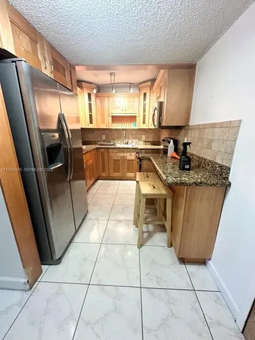 a kitchen with stainless steel appliances granite countertop a sink a stove a washer dryer and a view of living room