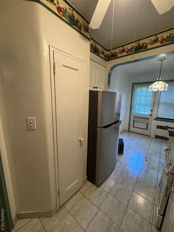 a view of a refrigerator in kitchen and an empty room