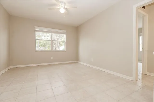 an empty room with chandelier fan and windows