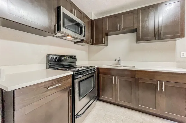a kitchen with stainless steel appliances granite countertop a sink a stove and microwave