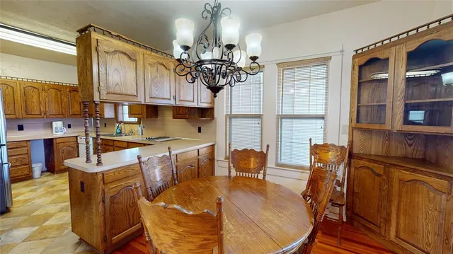 a kitchen with stainless steel appliances kitchen island granite countertop a table chairs in it and wooden floors