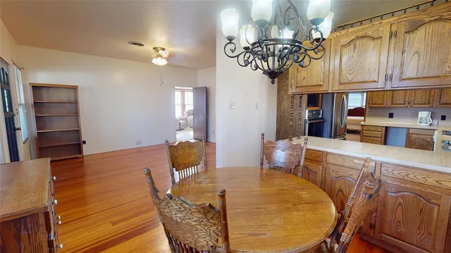 a kitchen with stainless steel appliances kitchen island granite countertop a table chairs in it and wooden floors