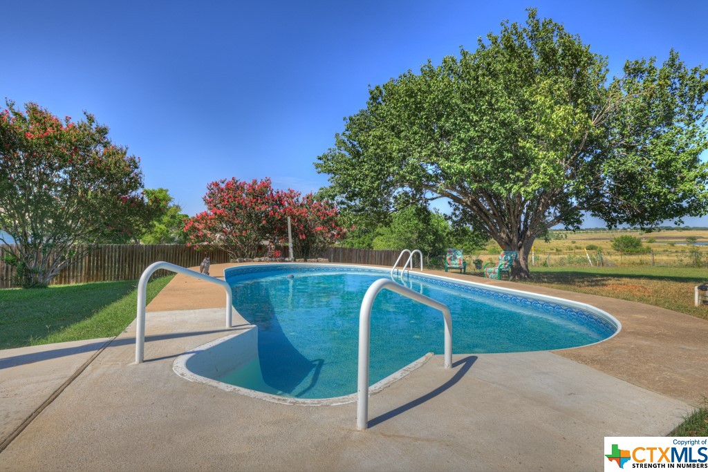 a view of swimming pool with a backyard and trees