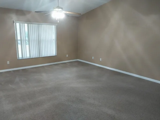 en empty room with windows and chandelier fan