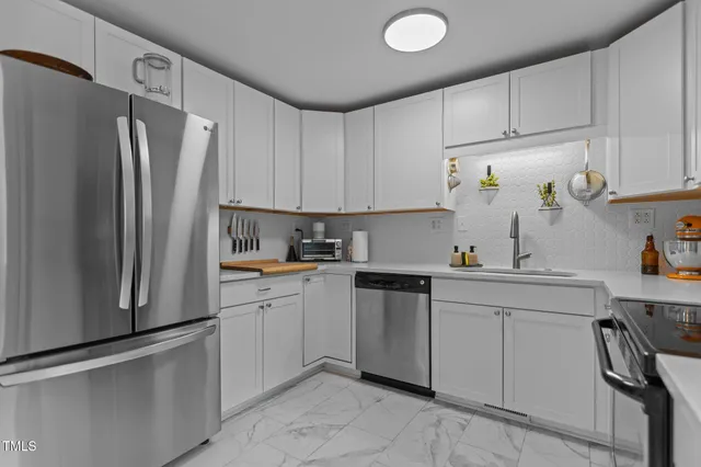 a kitchen with stainless steel appliances granite countertop a refrigerator sink and white cabinets