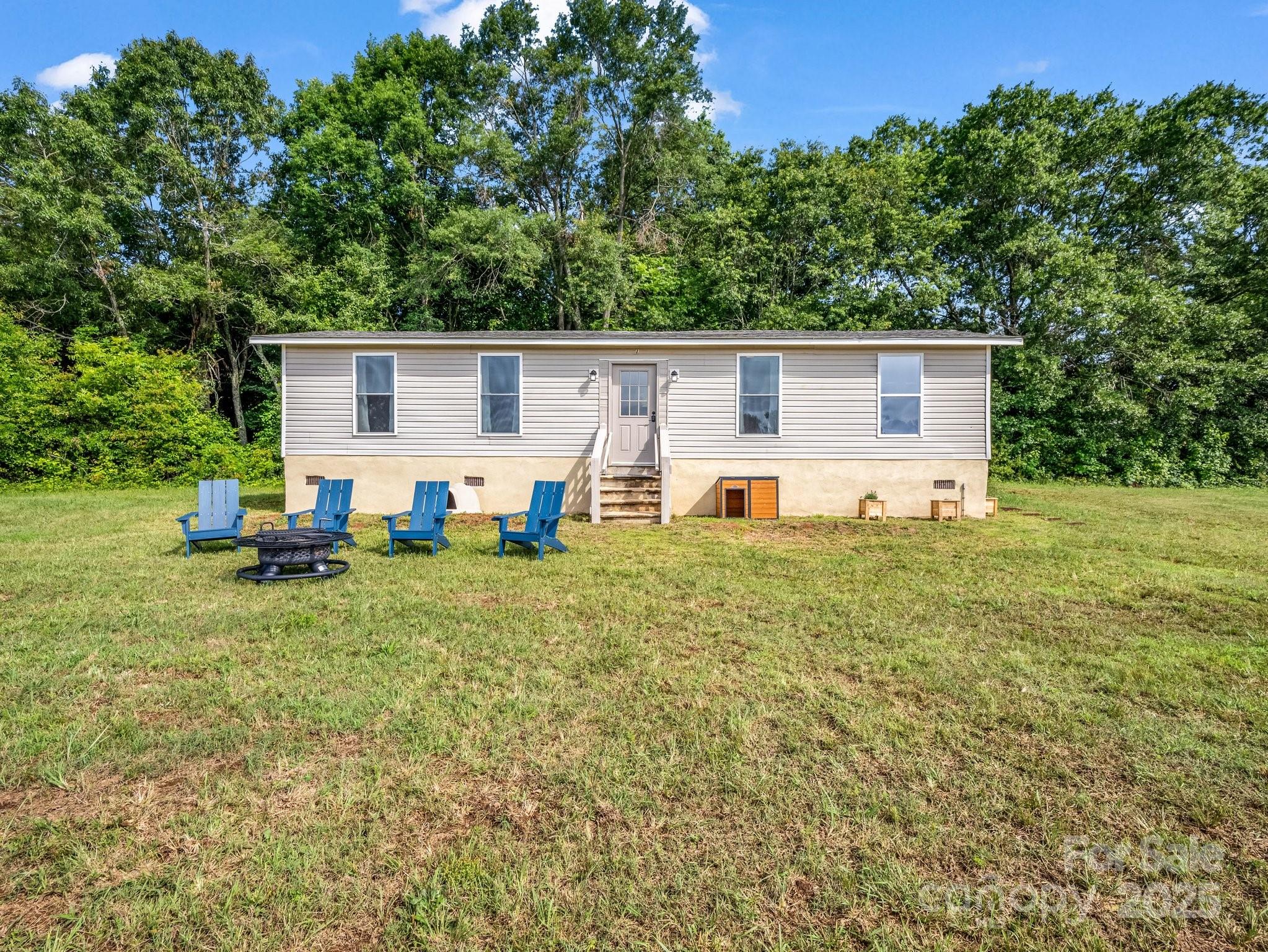 a view of a backyard with table and chairs plants and large tree