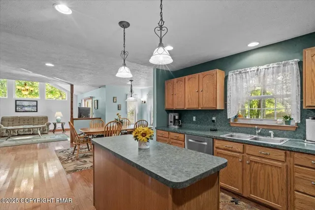 a kitchen with stainless steel appliances granite countertop wooden cabinets a stove a sink a dining table and chairs