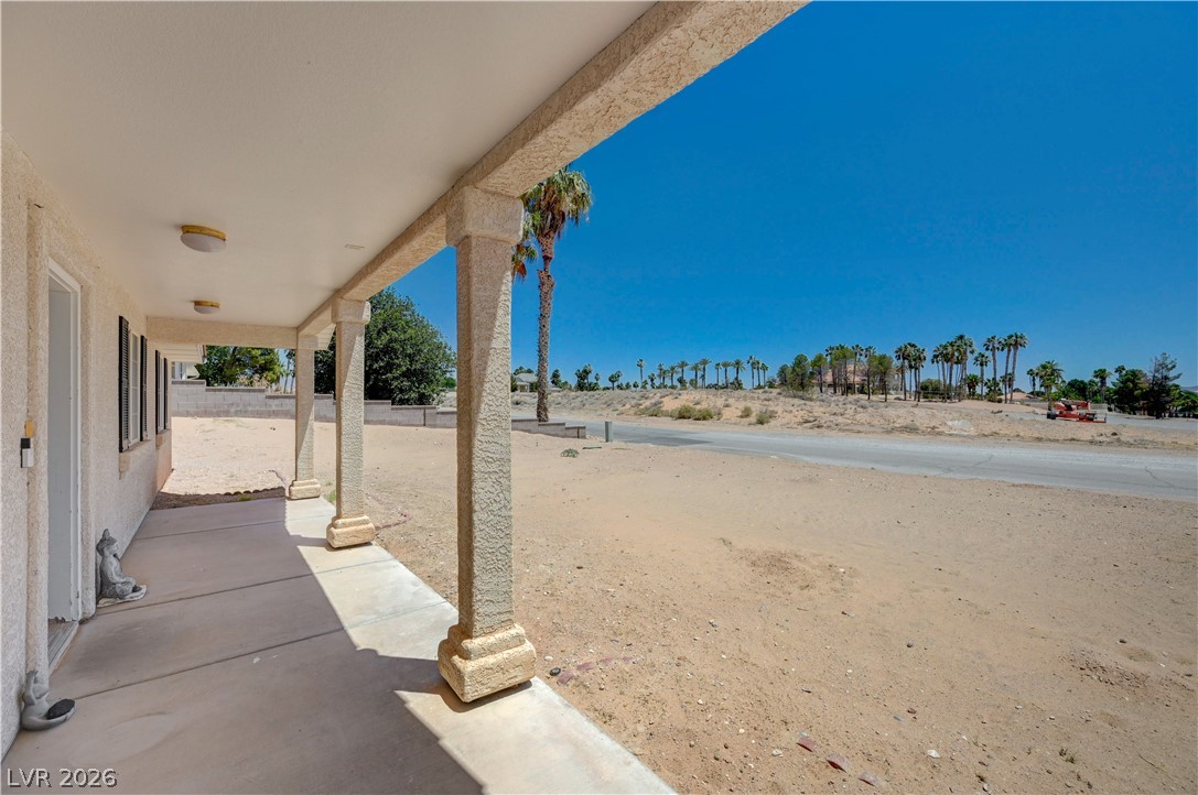 1272 Liston Avenue Logandale, NV 89021 - Photo 6 of 61 A spacious covered porch overlooks a desert landscape with distant palm trees and clear skies.