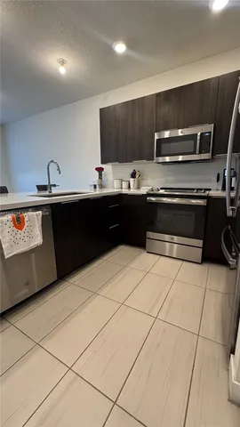 a kitchen with stainless steel appliances a sink a stove a microwave and cabinets