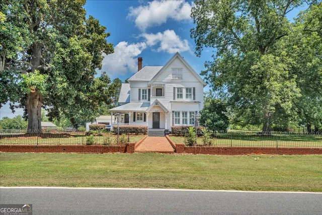 a front view of a house with a garden and trees