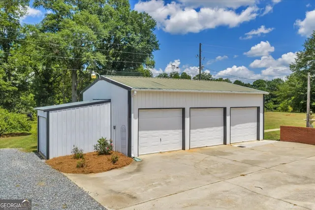 a white house with a large pool and lawn chairs under an umbrella