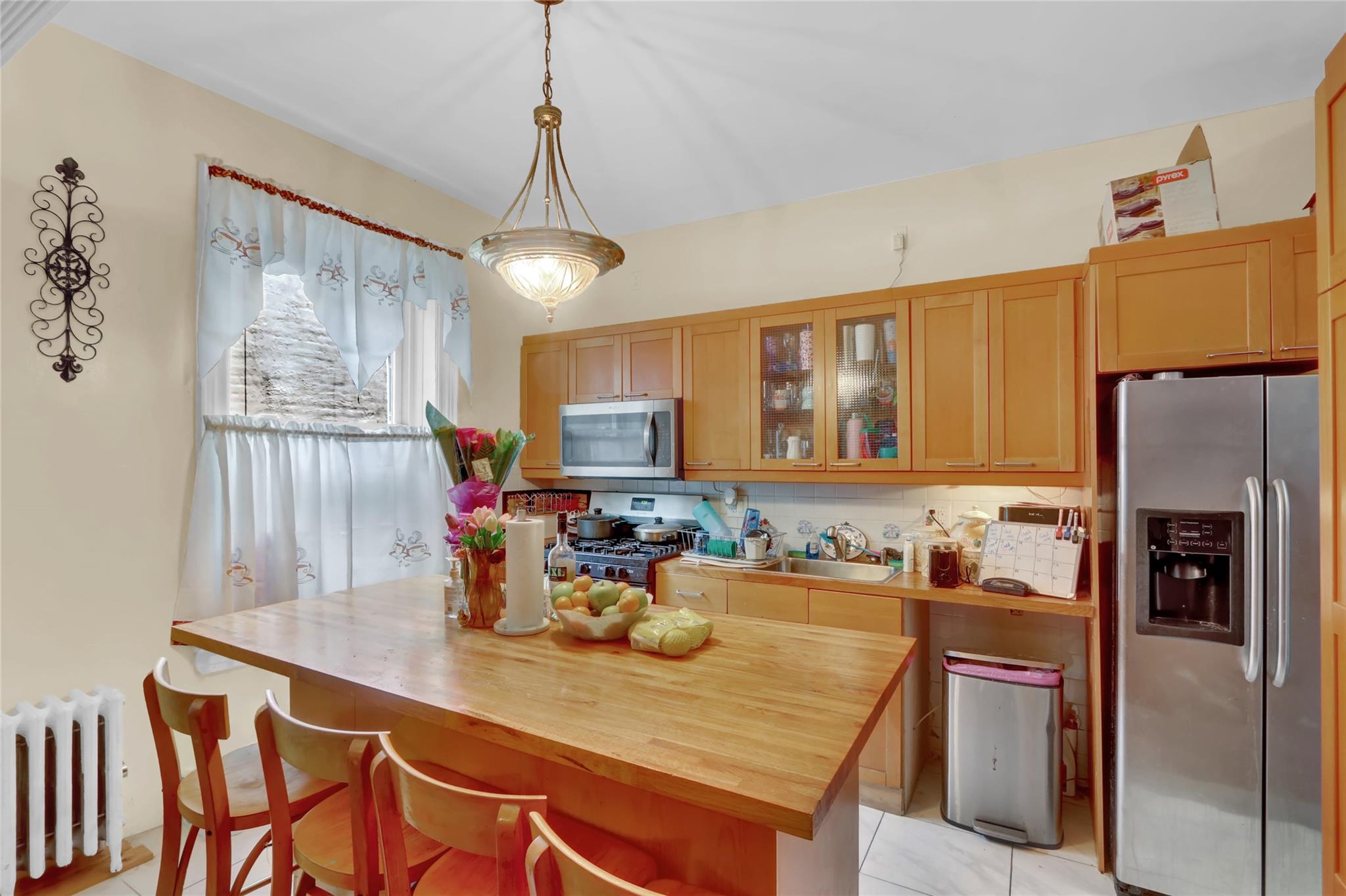 31 Tapscott Street Brooklyn, NY 11212 - Photo 6 of 10 Kitchen with appliances with stainless steel finishes, radiator, butcher block countertops, light tile patterned floors, and glass insert cabinets