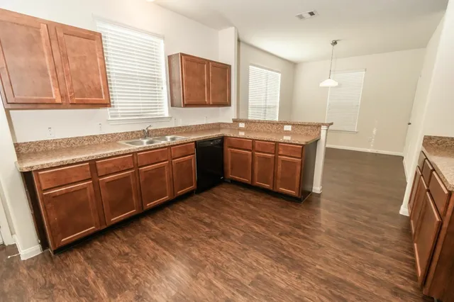 a kitchen with stainless steel appliances granite countertop a sink and a granite counter tops with wooden floors