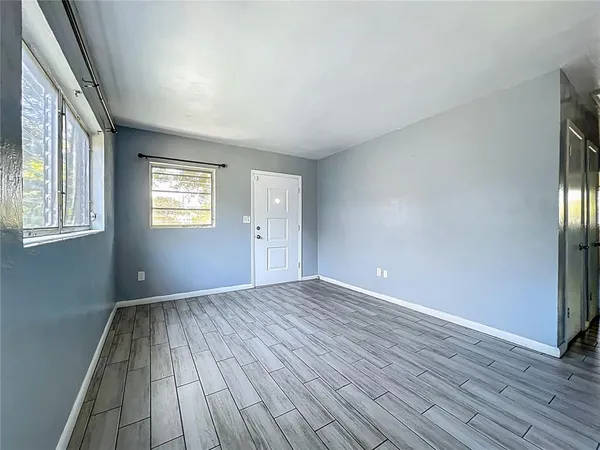 a view of an empty room with wooden floor and a window