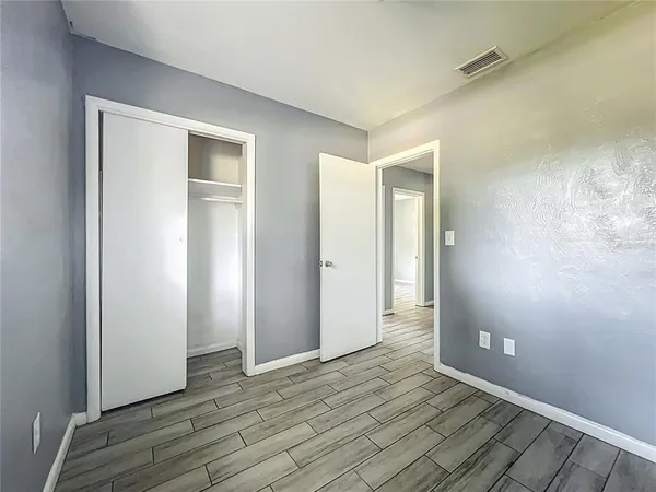 a view of an empty room with wooden floor and a bathroom