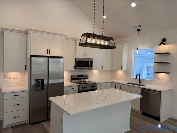 a kitchen with stainless steel appliances granite countertop a sink a stove a refrigerator and island