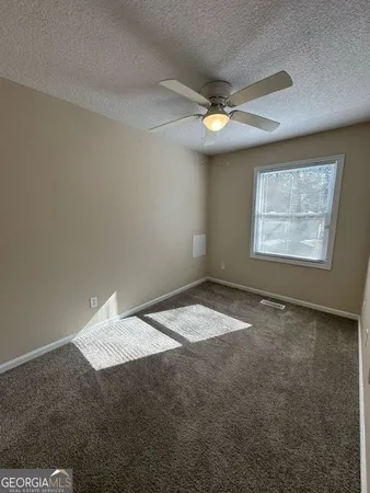 an empty room with a ceiling fan and window
