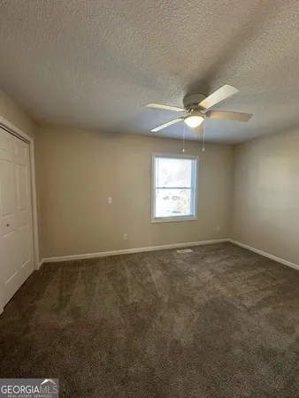 an empty room with a window and a fan