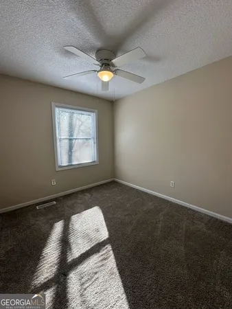 an empty room with windows and ceiling fan view