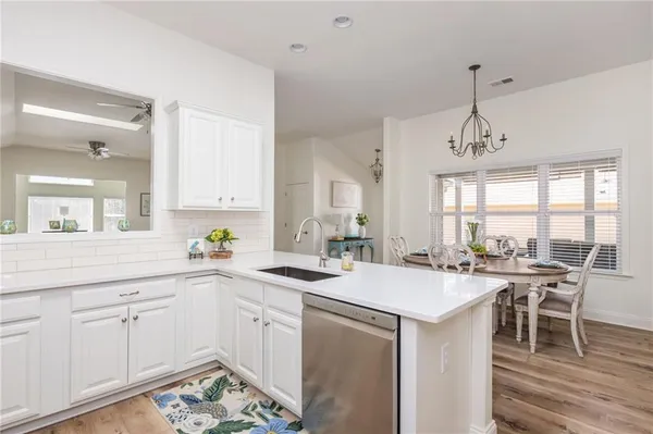 a kitchen with sink stove and white cabinets with wooden floor