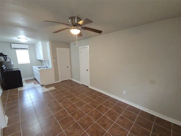 an empty room with kitchen and chandelier fan