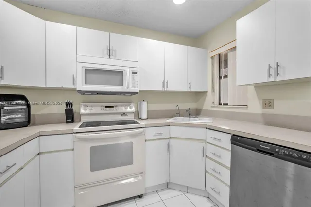 a kitchen with cabinets appliances a sink and a counter top space