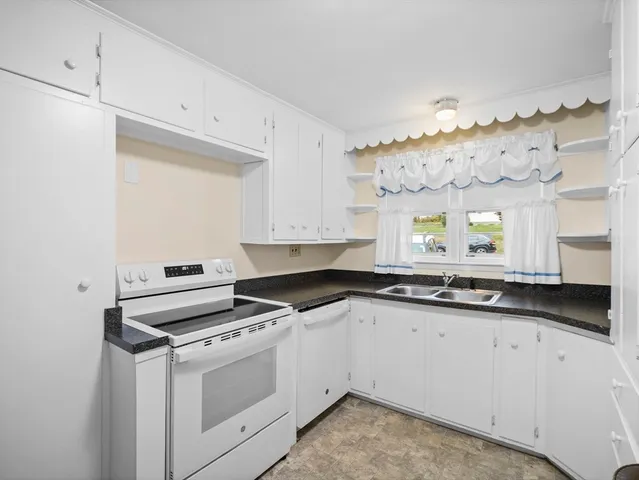 a kitchen with granite countertop a sink a stove and cabinets