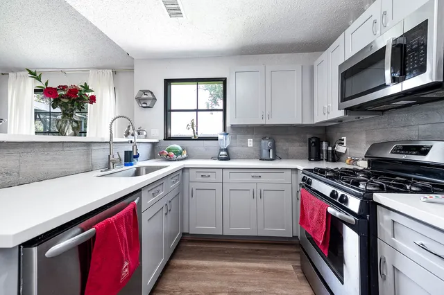 a kitchen with stainless steel appliances granite countertop a sink dishwasher stove and microwave with wooden cabinets