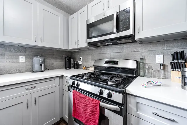 a kitchen with stainless steel appliances granite countertop a stove a microwave and cabinets