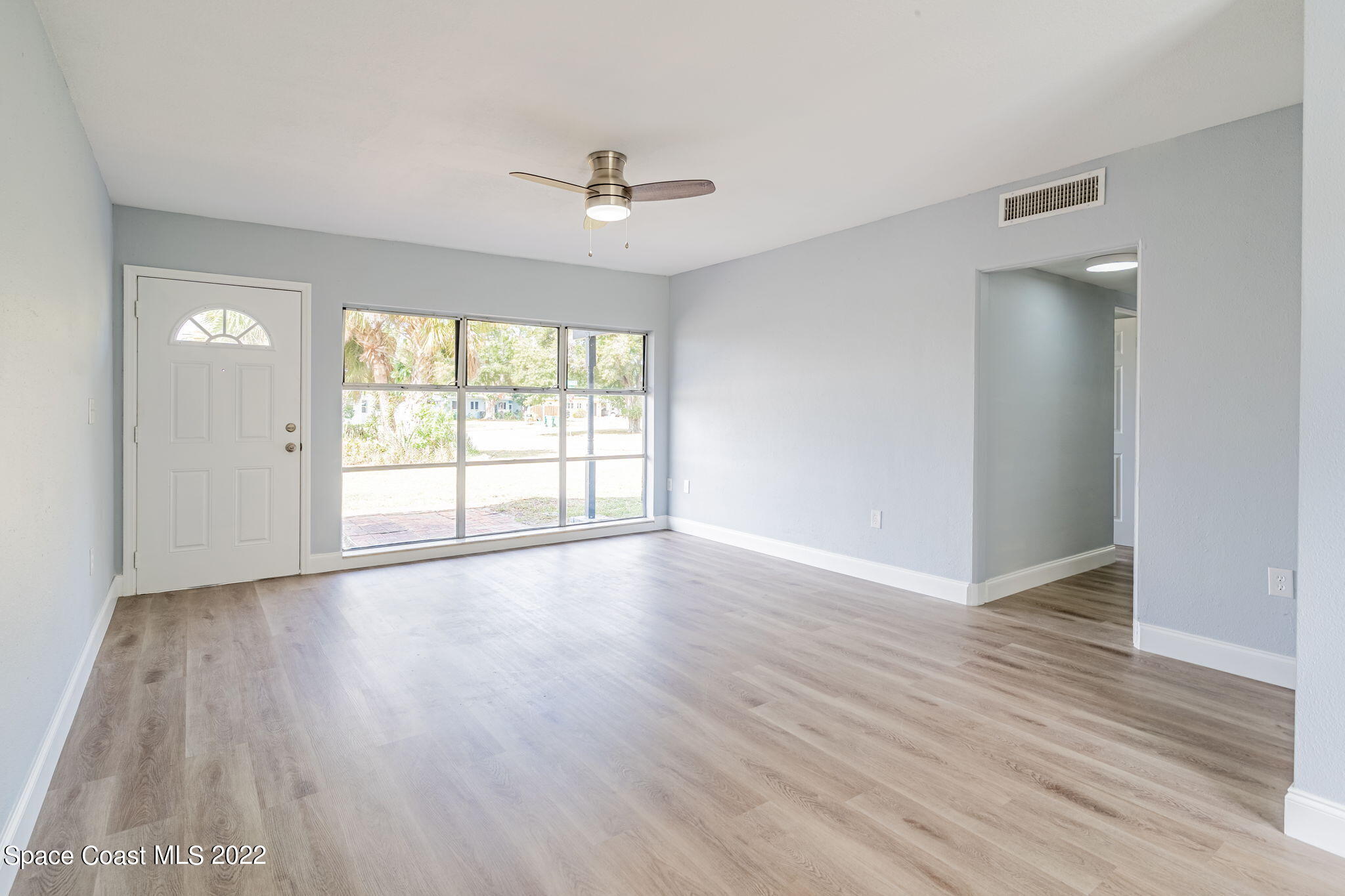 302 Prospect Avenue Cocoa, FL 32922 - Photo 5 of 28 an empty room with wooden floor chandelier fan and windows