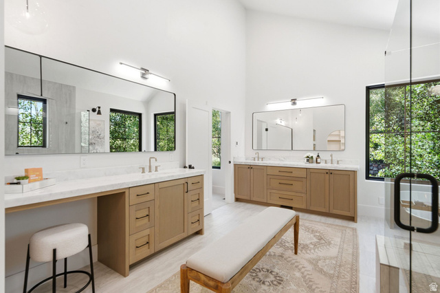 3027 Homestead Road Park City, UT 84098 - Photo 28 of 62 Spacious bathroom featuring twin wood-finish vanities with marble-look countertops and integrated sinks, large rectangular mirrors, and a glass-enclosed shower with black-framed windows