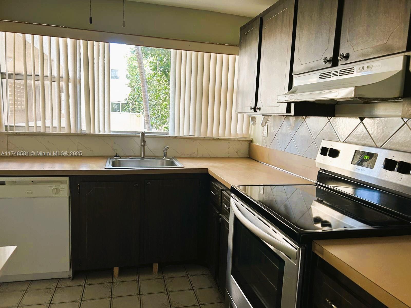 942 Northeast 199th Street, Unit 3E Miami, FL 33179 - Photo 11 of 31 a kitchen with a stove and a sink