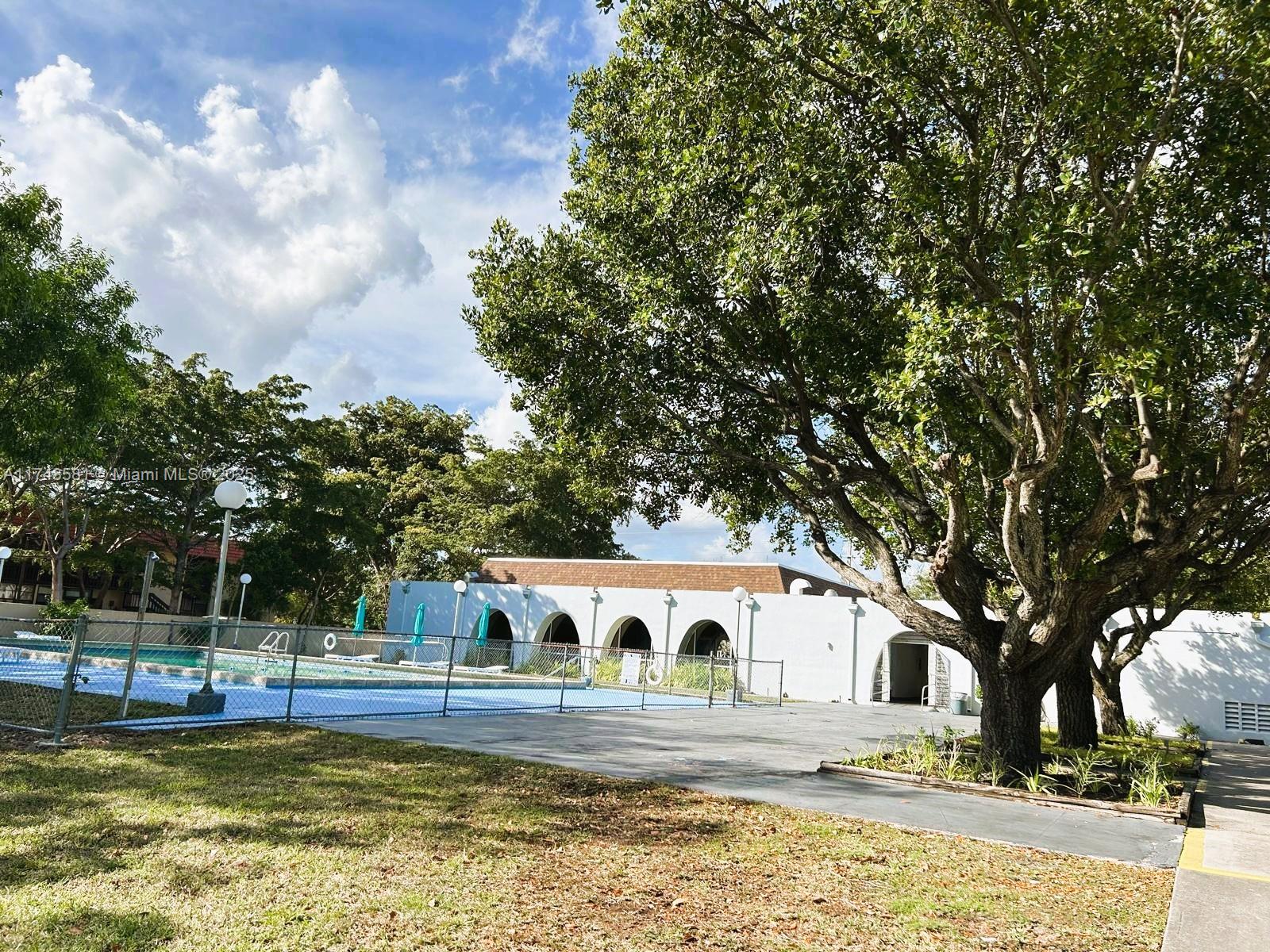 942 Northeast 199th Street, Unit 3E Miami, FL 33179 - Photo 28 of 31 a front view of a house with a large tree