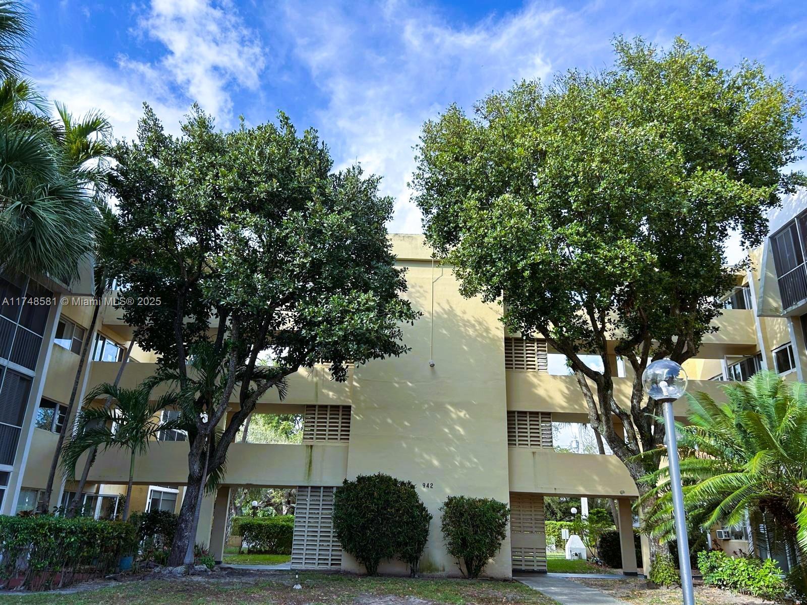 942 Northeast 199th Street, Unit 3E Miami, FL 33179 - Photo 3 of 31 a front view of a house with a tree