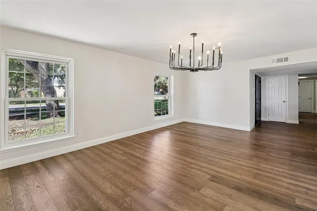 a view of empty room with wooden floor and window