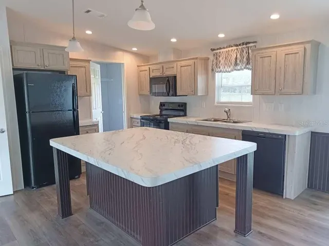 a kitchen with kitchen island a sink refrigerator and microwave