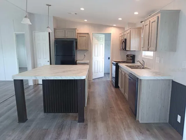 a large kitchen with a center island wooden floor stainless steel appliances and cabinets