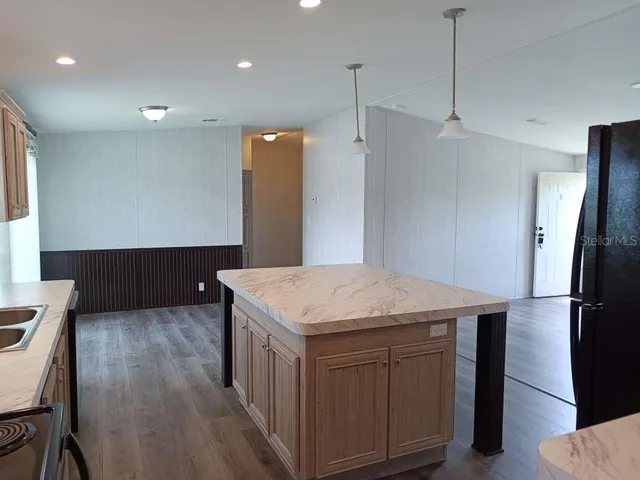 a kitchen with kitchen island a sink dishwasher a refrigerator and wooden floor