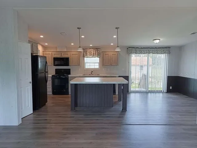 a large kitchen with kitchen island a sink wooden floor and stainless steel appliances