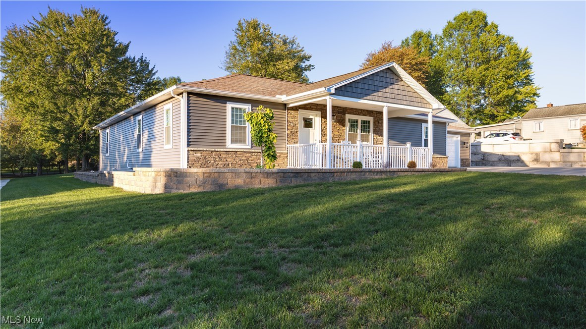 6264 Herbert Road Canfield, OH 44406 - Photo 39 of 47 View of front facade featuring stone siding, a front lawn, and covered porch